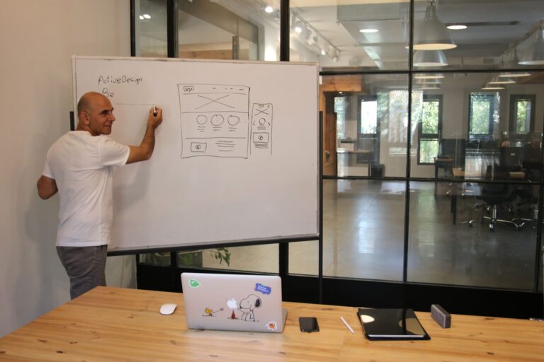 Un homme dessine le plan des pages au tableau blanc