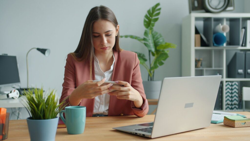 Femme qui prépare une publication entre ordinateur et téléphone