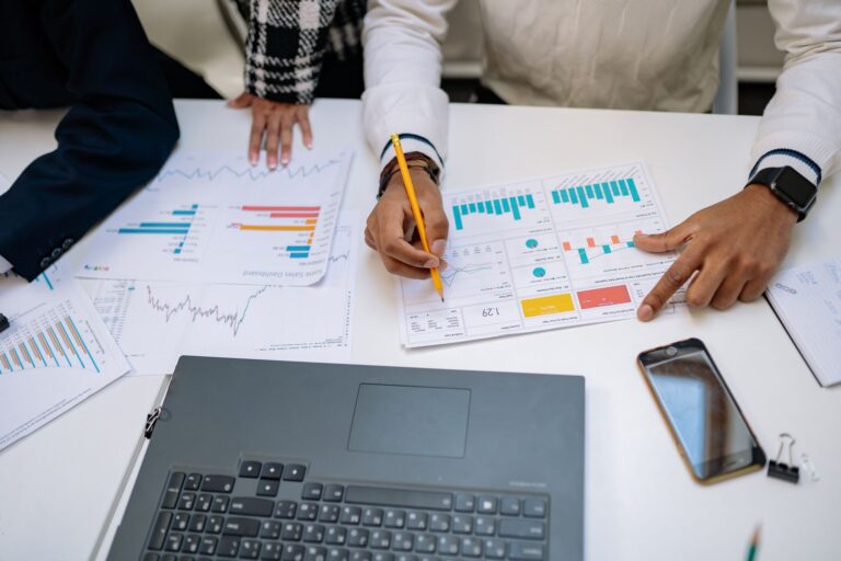 Mains qui analysent des graphiques imprimés à côté d’un ordinateur portable pendant un audit